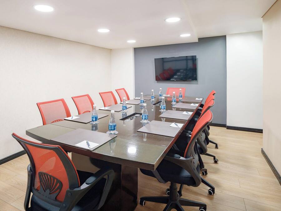 A conference room with a long table, red chairs, and water bottles.