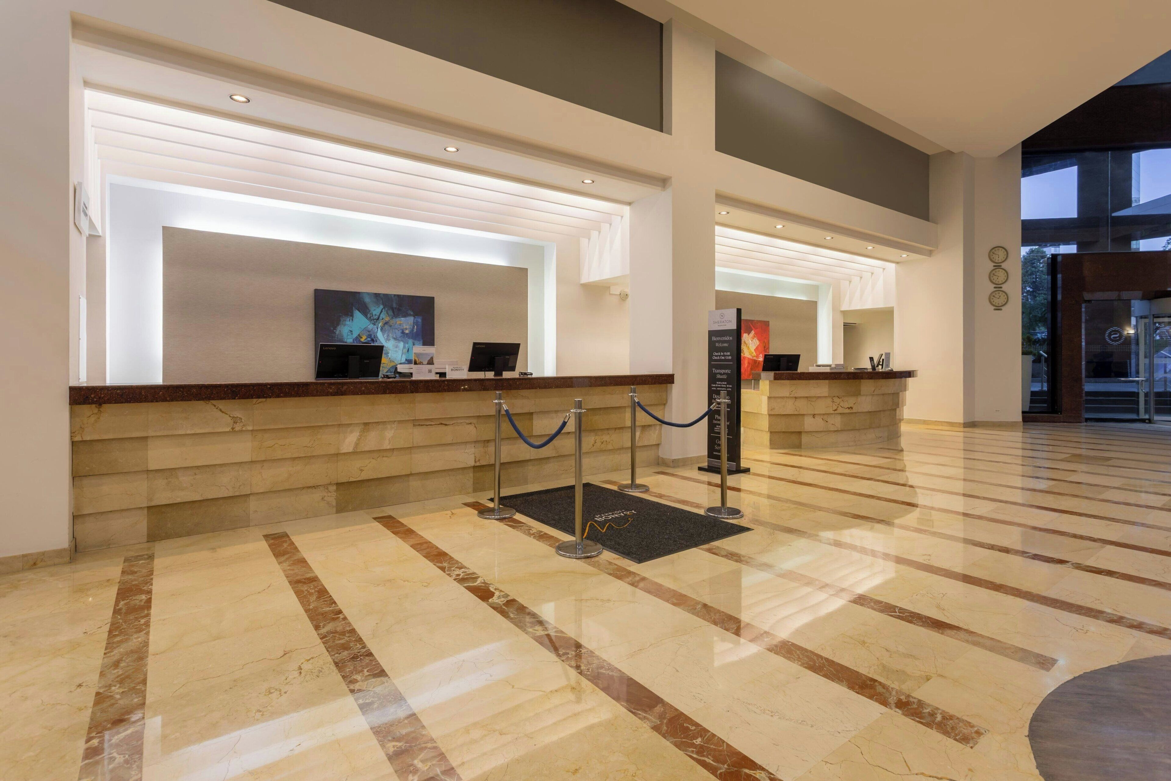 A hotel reception area with marble flooring, a reception desk, and a modern interior design.