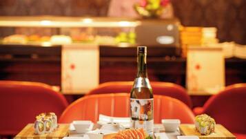 Entorn de restaurant amb un plat de sushi, una ampolla i un xef al fons.