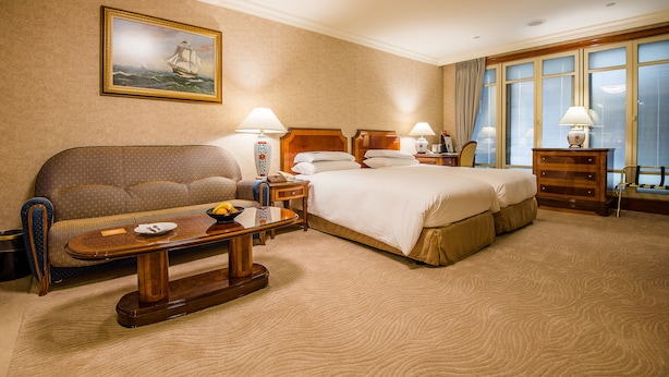 A hotel room with a large bed, a sofa, a wooden coffee table, and a painting on the wall. - Evergreen Laurel Hotel Taipei (Taipei)
