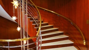 A spiral staircase with a golden handrail and star-shaped hanging lights, leading to a higher floor. - Evergreen Laurel Hotel Taipei (Taipei)