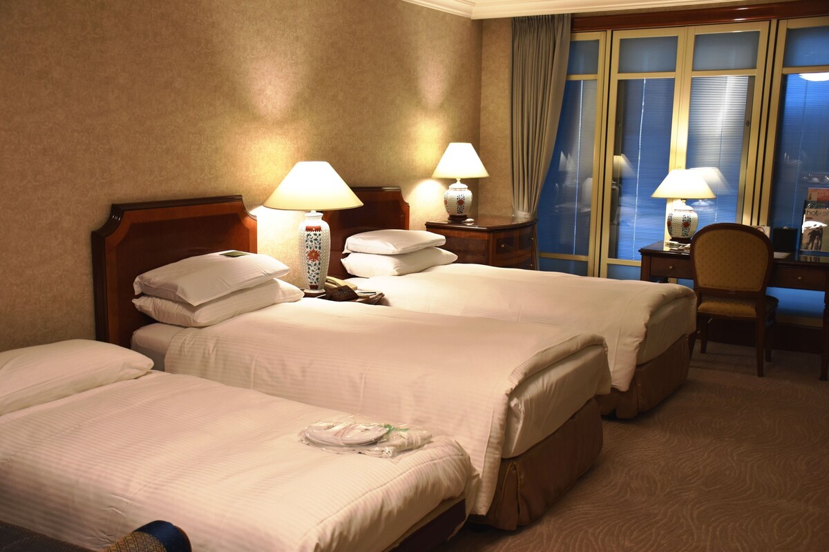A hotel room with two beds, a desk, and a chair.