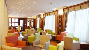 A hotel lobby with multiple seating areas, including chairs and tables. There are large windows with curtains, and the room has a wooden floor. - Evergreen Laurel Hotel Taipei (Taipei)