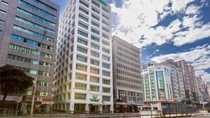 A modern hotel with a prominent green logo, multiple floors, and a clear view of the surrounding urban environment. - Evergreen Laurel Hotel Taipei (Taipei)