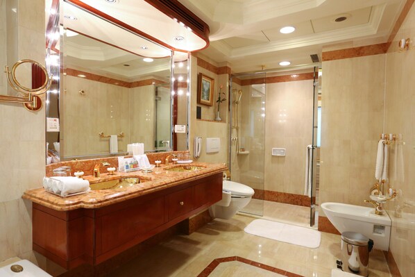 A luxurious bathroom with a double sink vanity, a large mirror, a glass-enclosed shower, and a white toilet.
