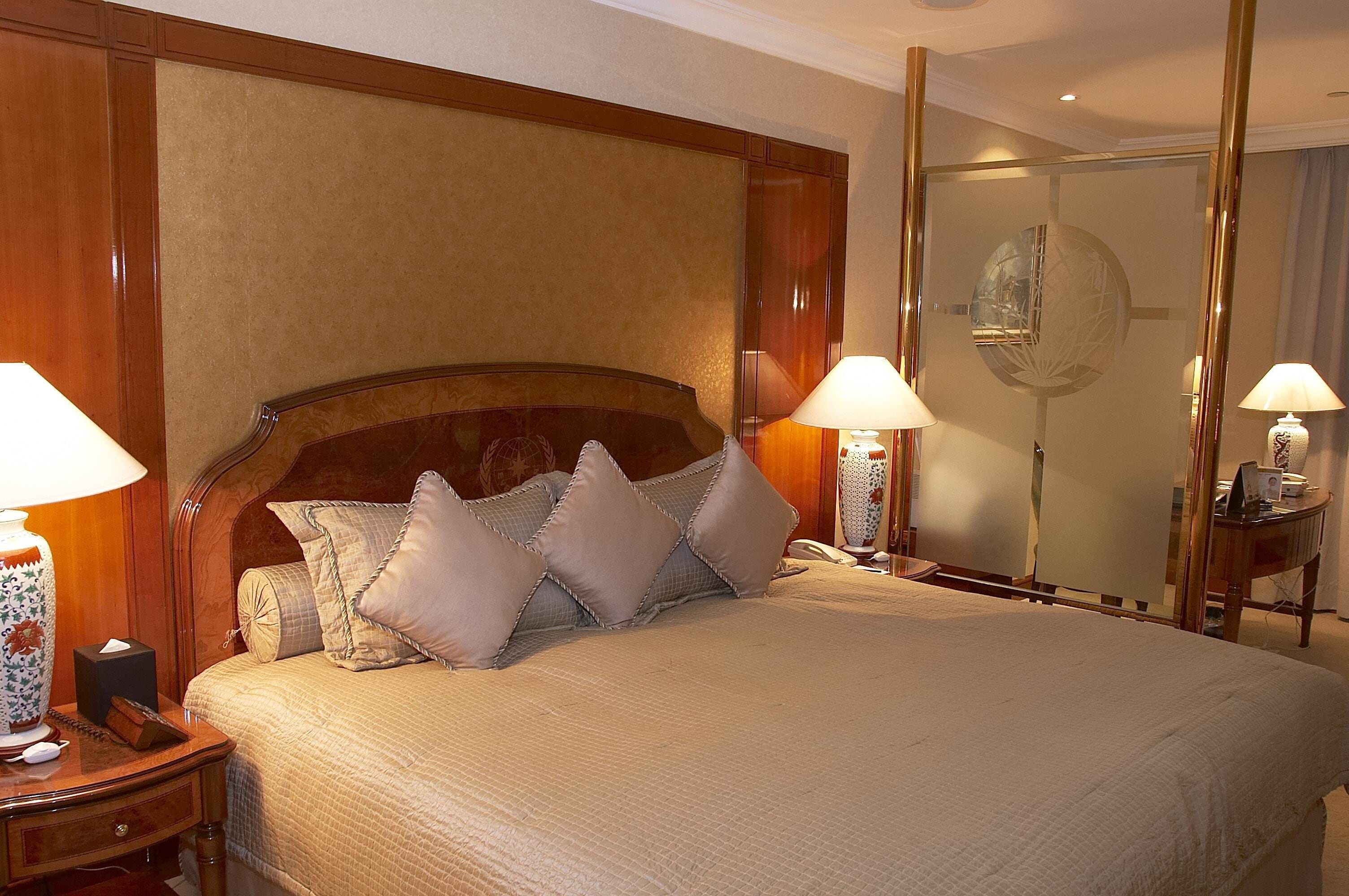 A hotel room with a large bed, two bedside lamps, a nightstand, and a mirror.
