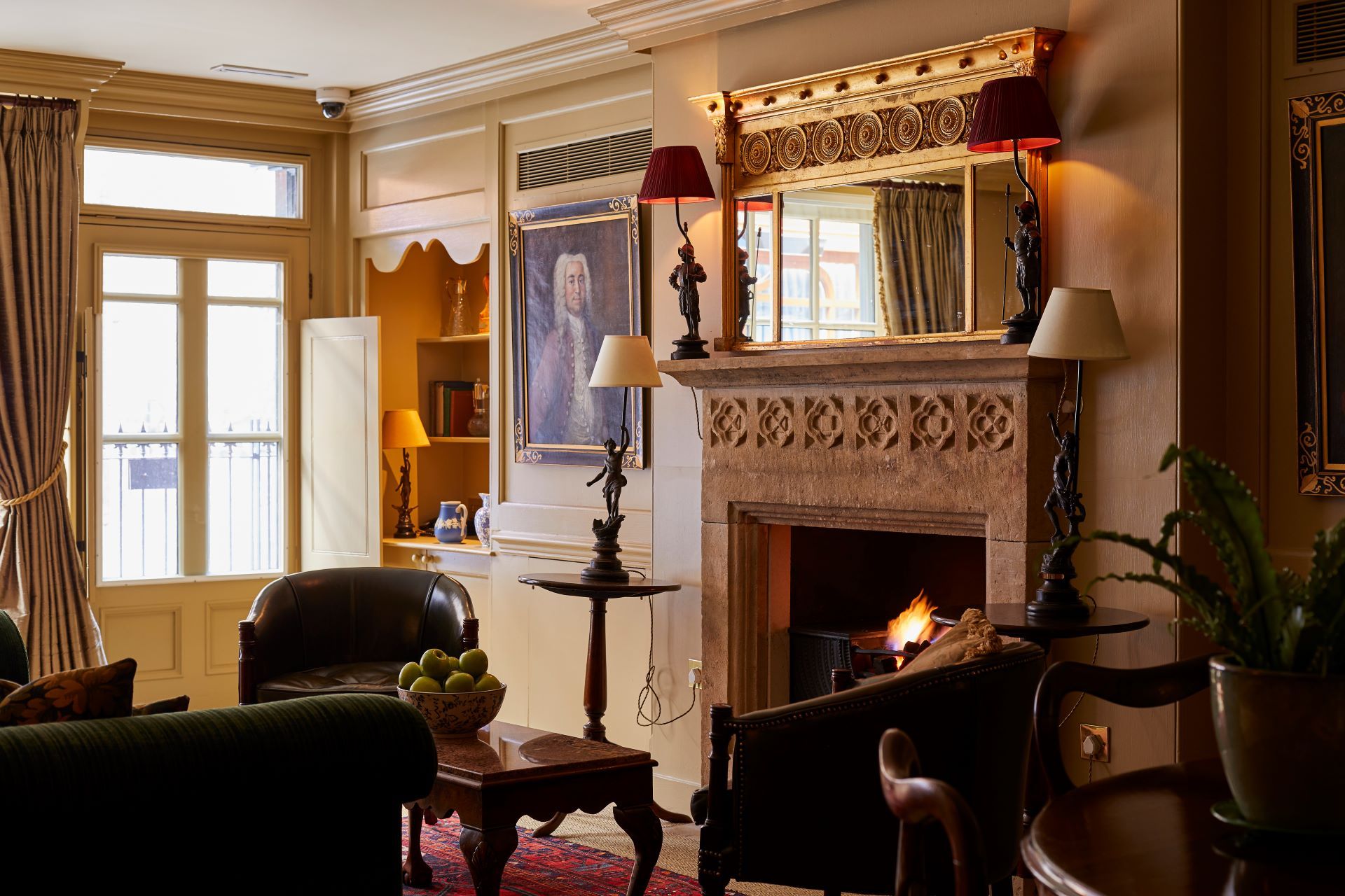 A traditional living room with a fireplace, leather furniture, and a large window.