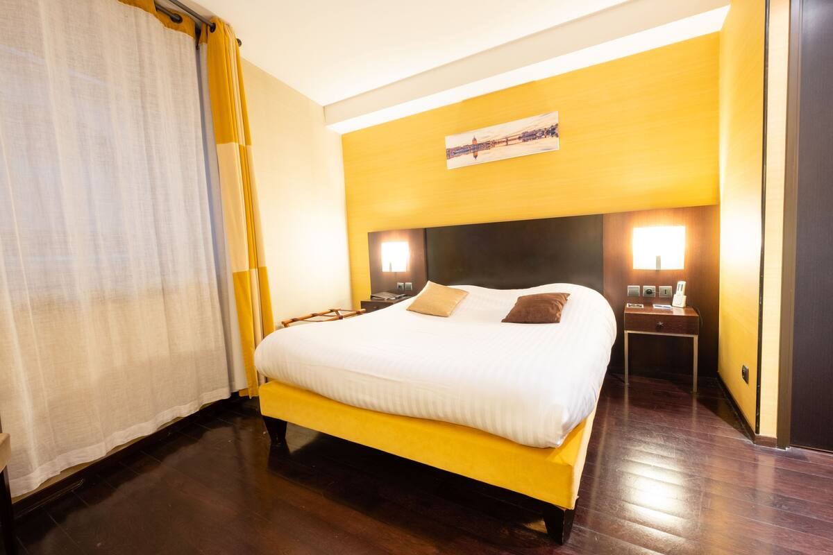 Une chambre d’hôtel avec un grand lit, un plancher en bois et deux tables de chevet avec des lampes.