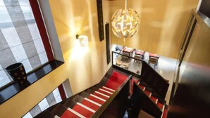 A modern hotel lobby with a checkered floor pattern, a staircase with red and white carpeting, and a spherical chandelier. - Le Boutique Hôtel Garonne by Occitania hotels (Toulouse)