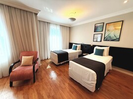 Una camera d'albergo con due letti, una sedia e un tavolino.