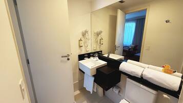 Un baño moderno con un espejo grande, un lavabo, un inodoro y una zona de ducha.