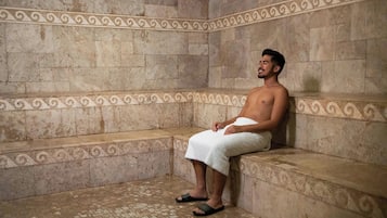 A man sitting on a bench in a room with tiled walls and a patterned border.