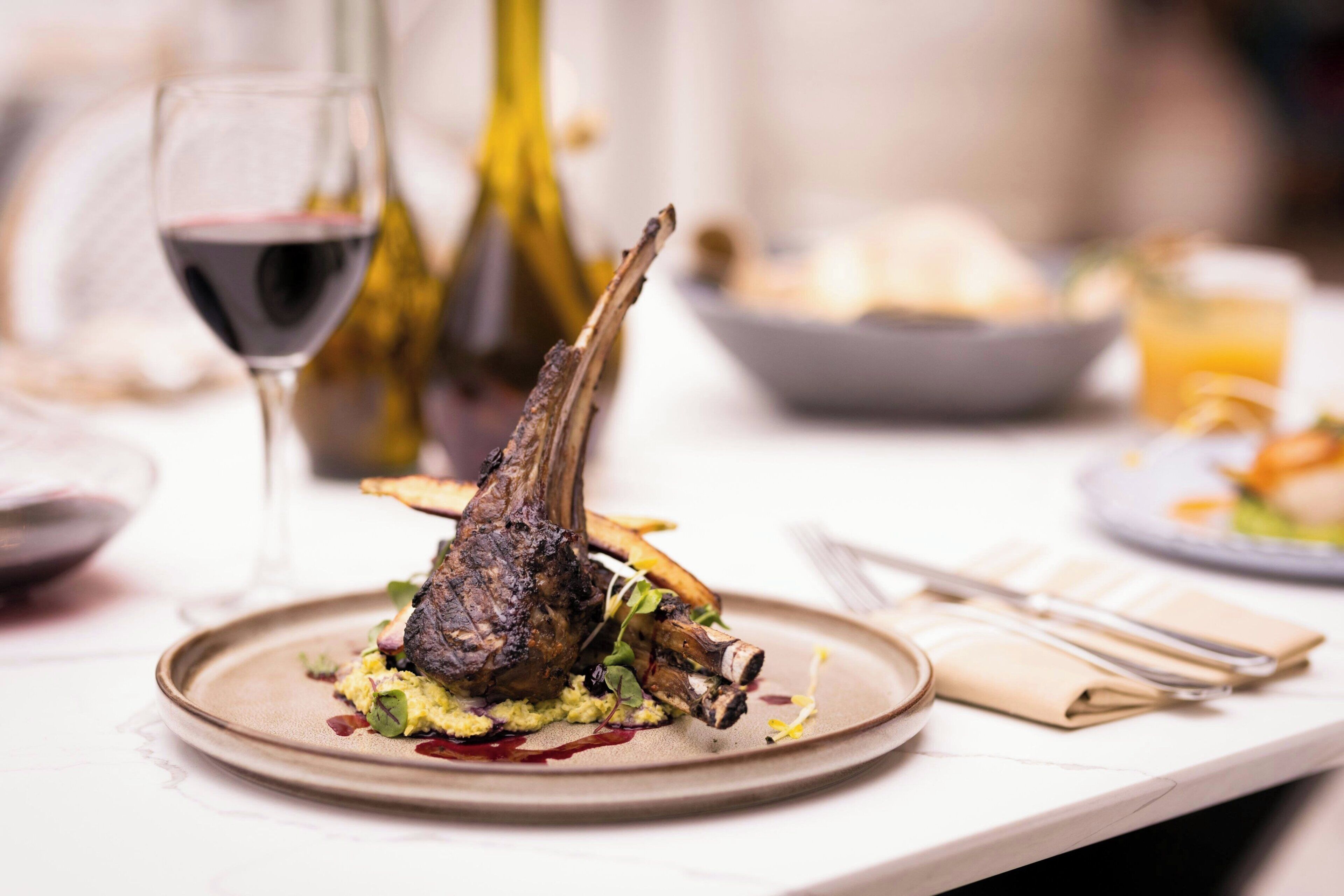 A dining table with a plate of food, a wine glass, and a bottle.