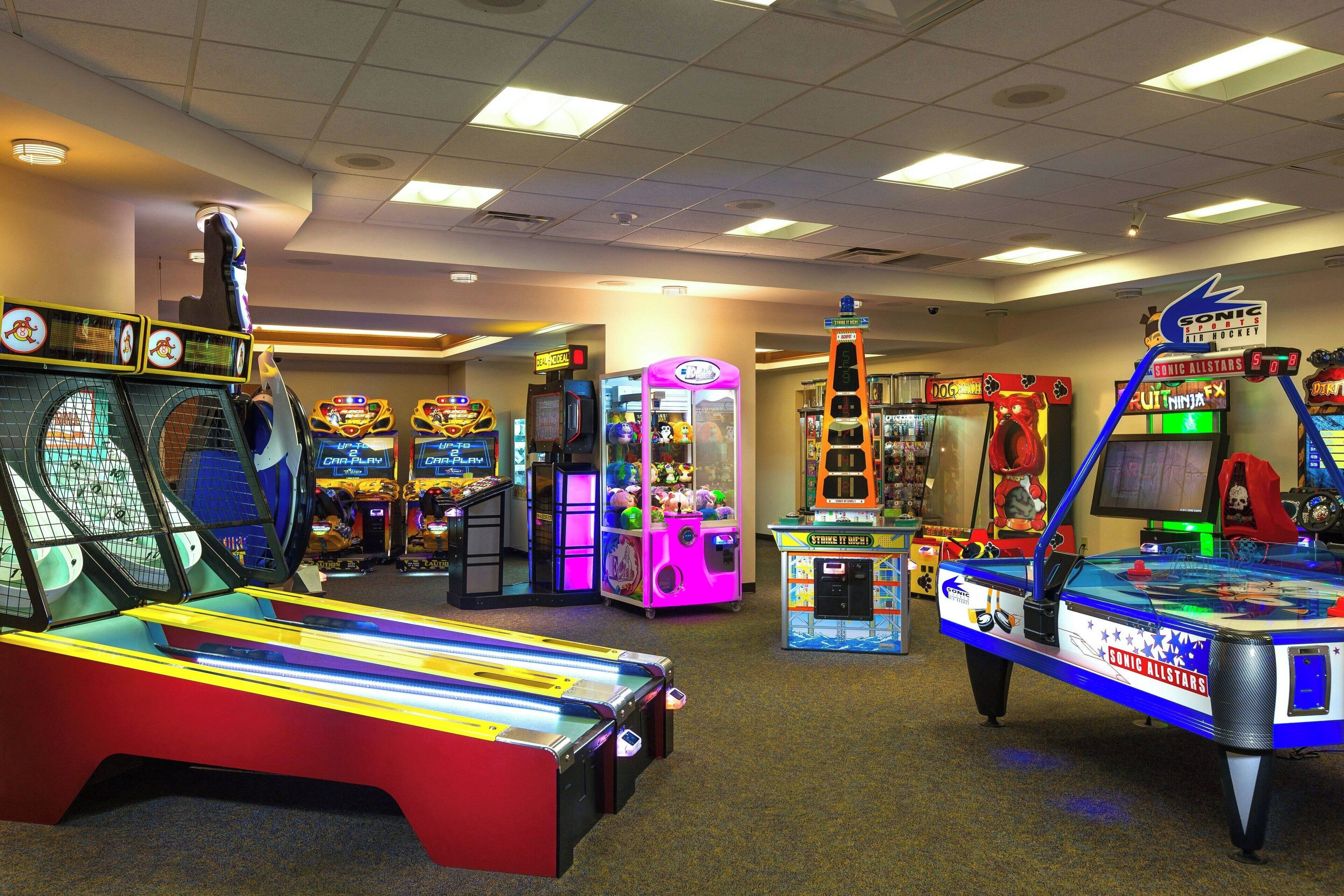 An indoor arcade with various gaming machines, including a pool table and claw machines.