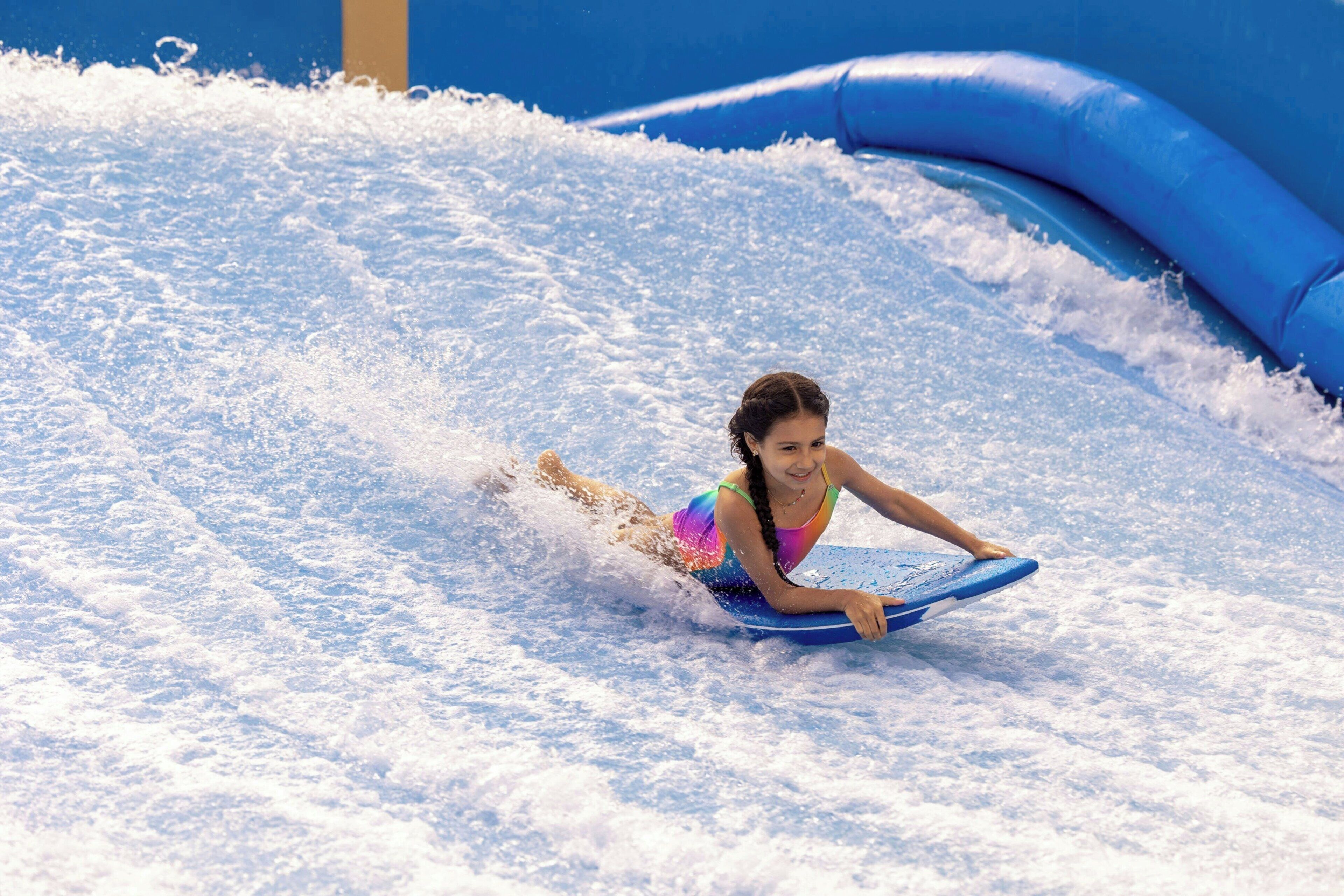 A person on a blue water slide in a water park.