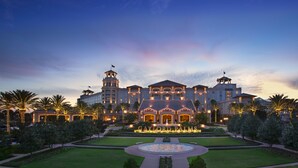 Een groot, meerhoog hotel met een centrale binnenplaats, palmbomen en verlichte borden.