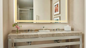 A modern bathroom with a large mirror, two sinks, and a wooden towel rack.
