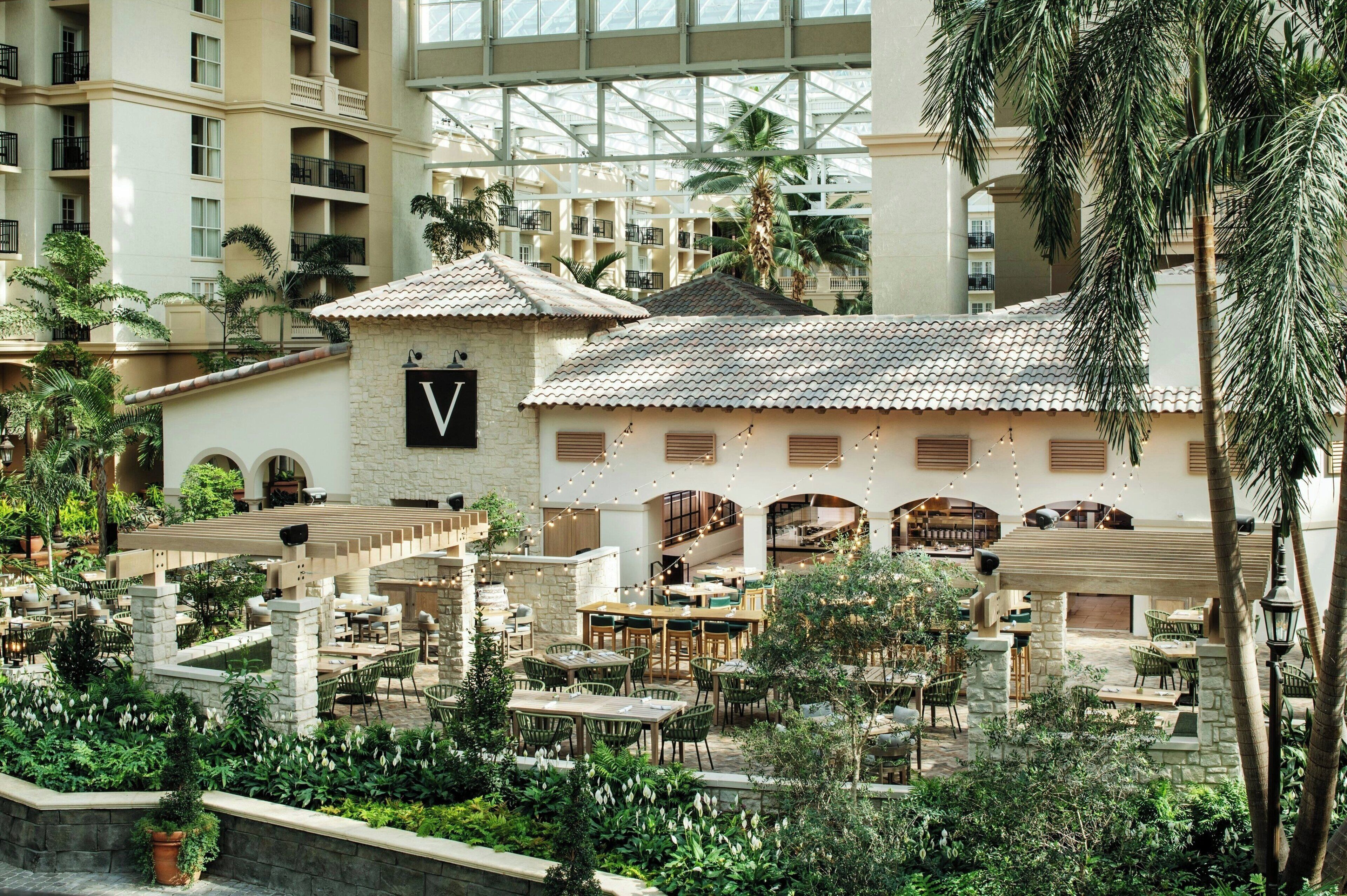 Un atrium d’hôtel comprenant plusieurs espaces de restauration, une cour intérieure et une vue sur les bâtiments environnants.