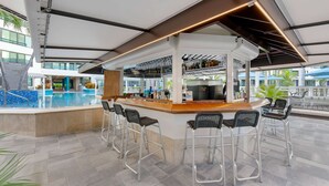 Een modern buitengebied met een bar, zwembad, barkrukken en uitzicht op het zwembad.