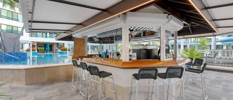A modern outdoor bar area with a pool, bar stools, and a view of the pool.