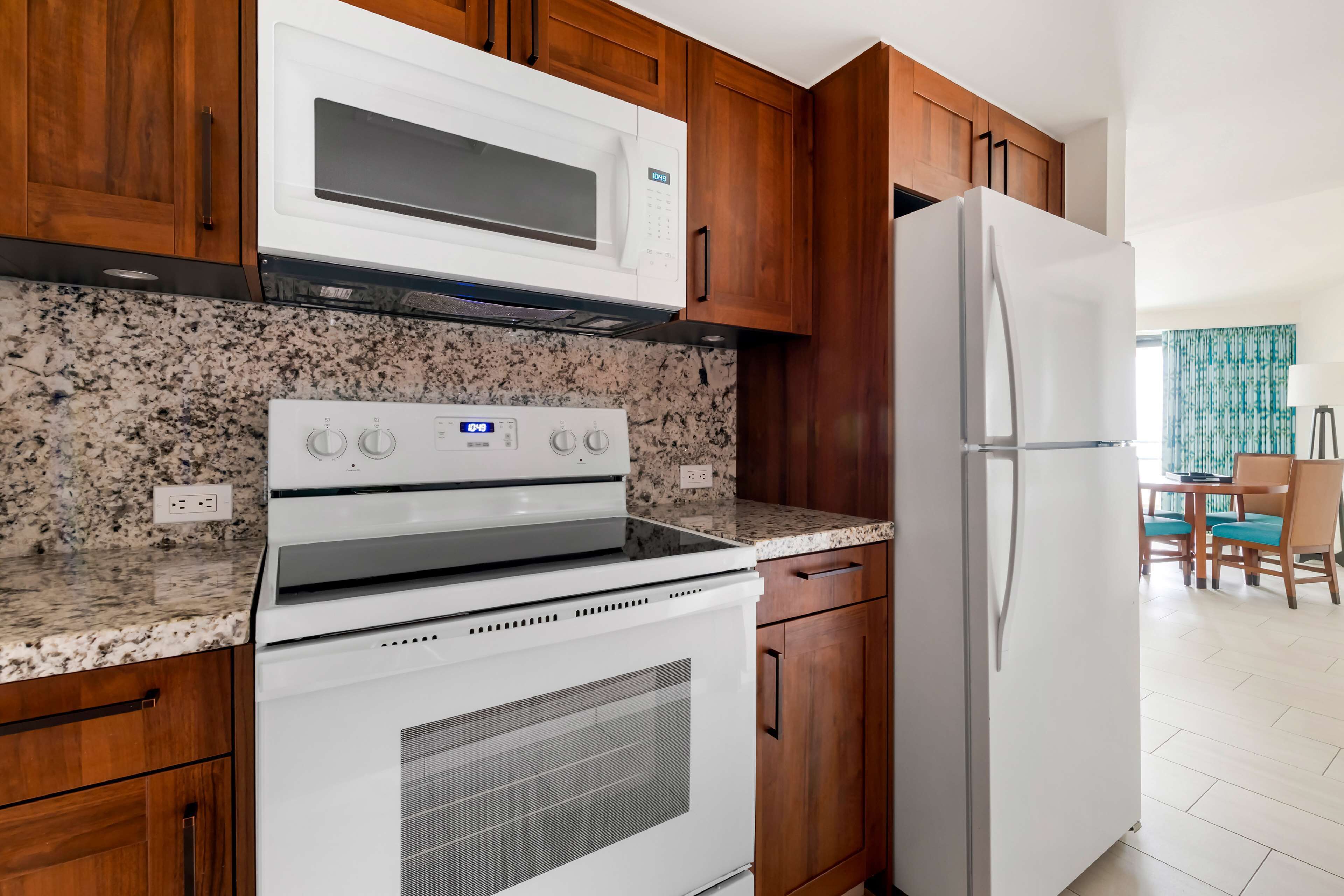 A kitchen with wooden cabinets, a white microwave, a stove, and a refrigerator.