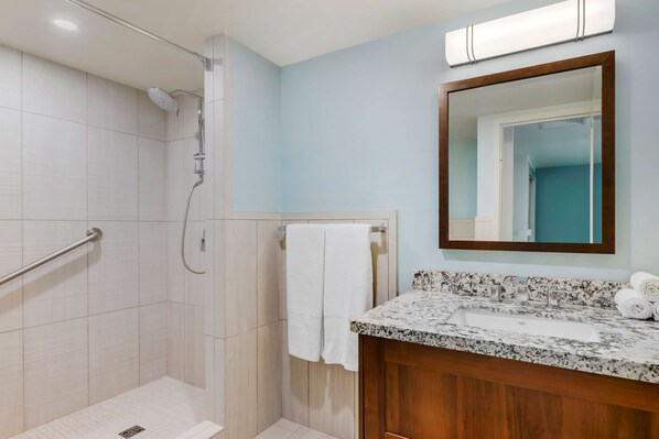 Un baño con ducha, lavabo y espejo.