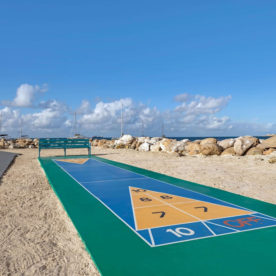 A shuffleboard court on a sandy beach with a clear sky.