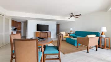 A modern living room with a sofa, chairs, a dining table, and a television.