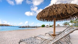 Een strand met ligbedden en een rieten parasol.