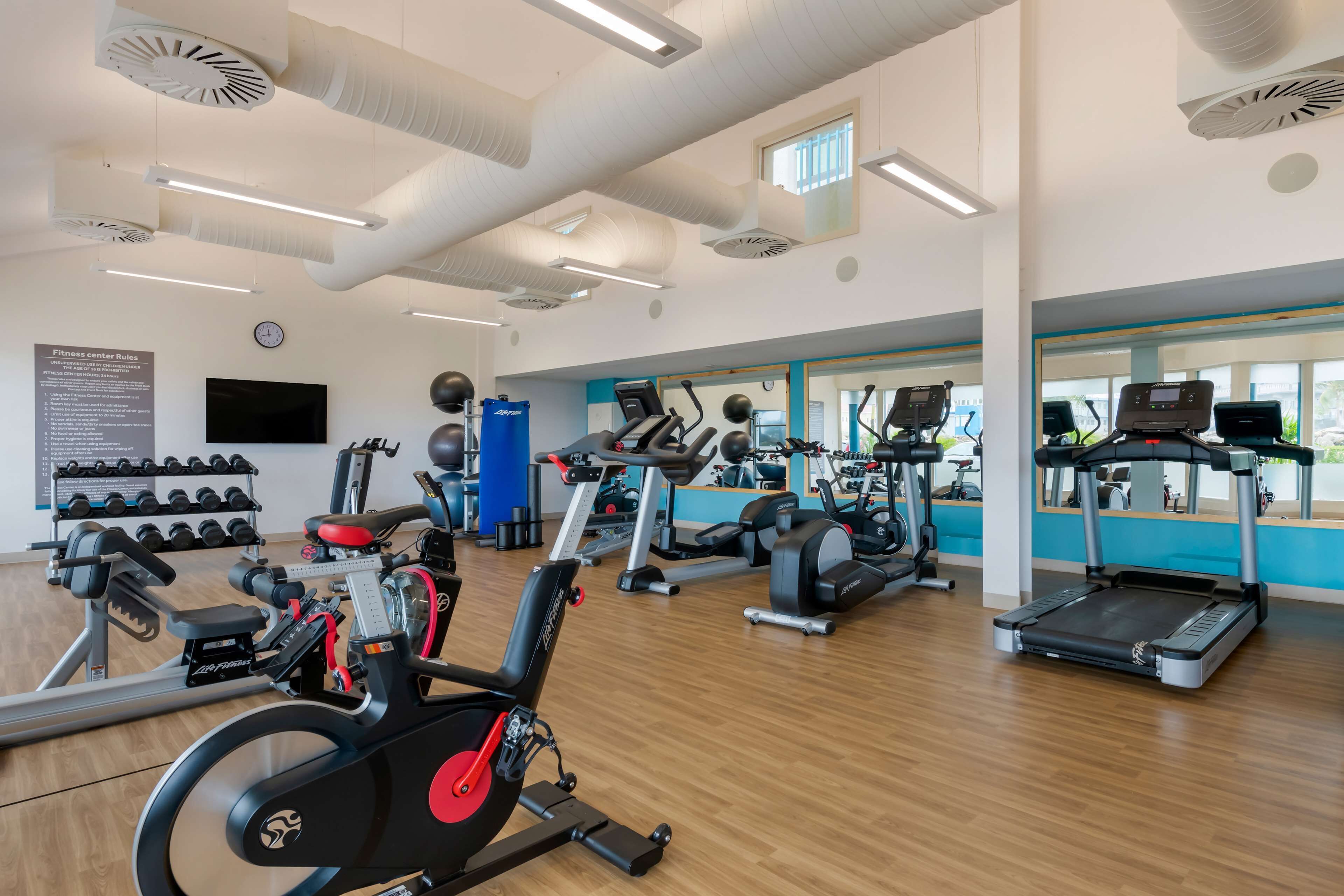 Un gimnasio con diferentes máquinas de ejercicio, incluyendo cintas de correr, bicicletas estáticas y máquinas de pesas.