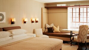 Una camera d'albergo con un letto grande, un'area salotto con tavolo e sedie, e una finestra vista.