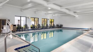 A swimming pool with a clear blue water, surrounded by lounge chairs and a sunroof.
