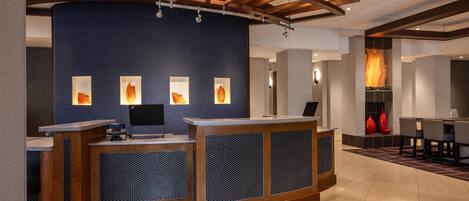 A reception area with a blue wall, wooden reception desk, and a fireplace.