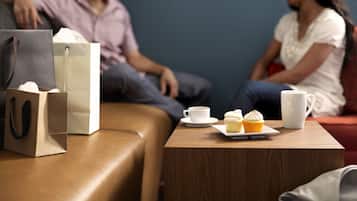 A wooden table with a cup of coffee, a muffin, and a white mug.