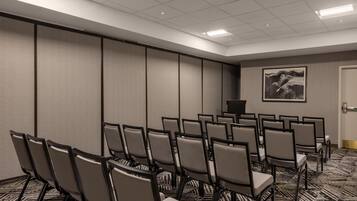 A conference room with rows of chairs, a podium, and a large painting on the wall.