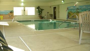 Una piscina interior con suelo de baldosas, una escalera de piscina y un mural en la pared.