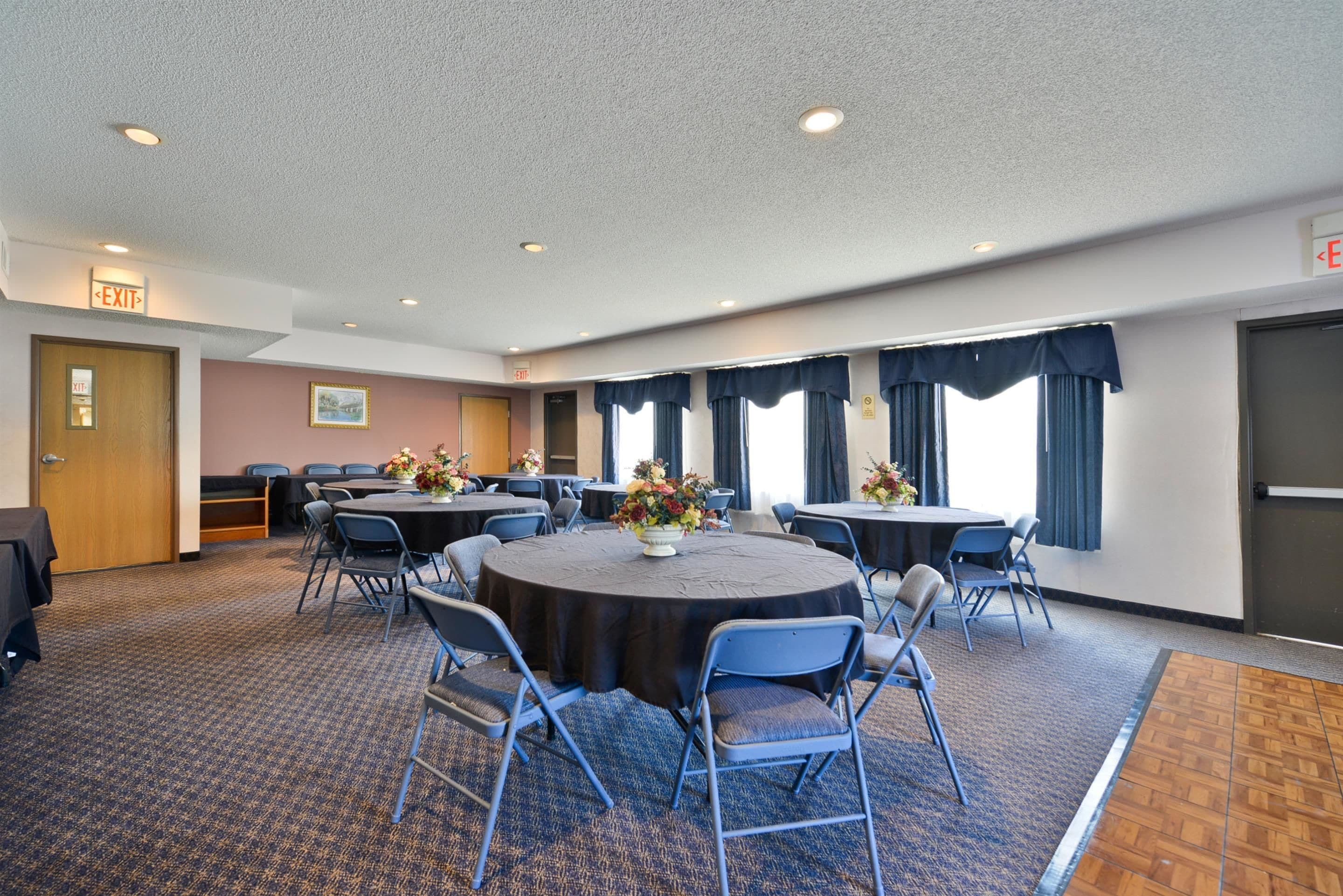 A conference room with a round table, chairs, and floral centerpieces.