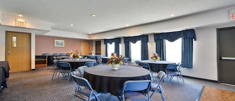 A conference room with a round table, chairs, and floral centerpieces.