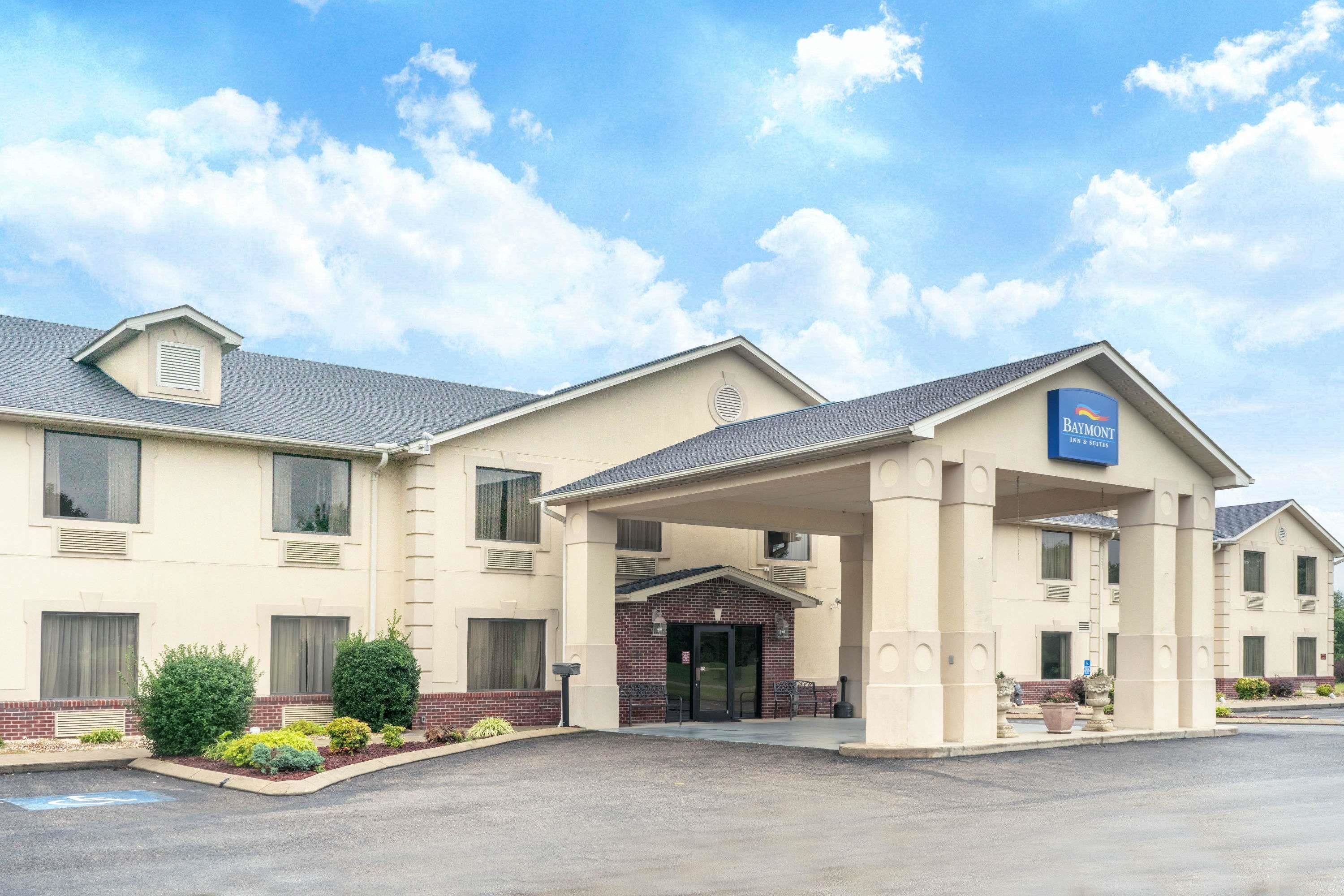 Un Baymont Inn & Suites con entrada cubierta, fachada de ladrillo y estacionamiento.