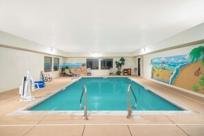 An indoor swimming pool with clear water, surrounded by lounge chairs and a mural depicting a beach scene. - Baymont by Wyndham Albany (Albany)