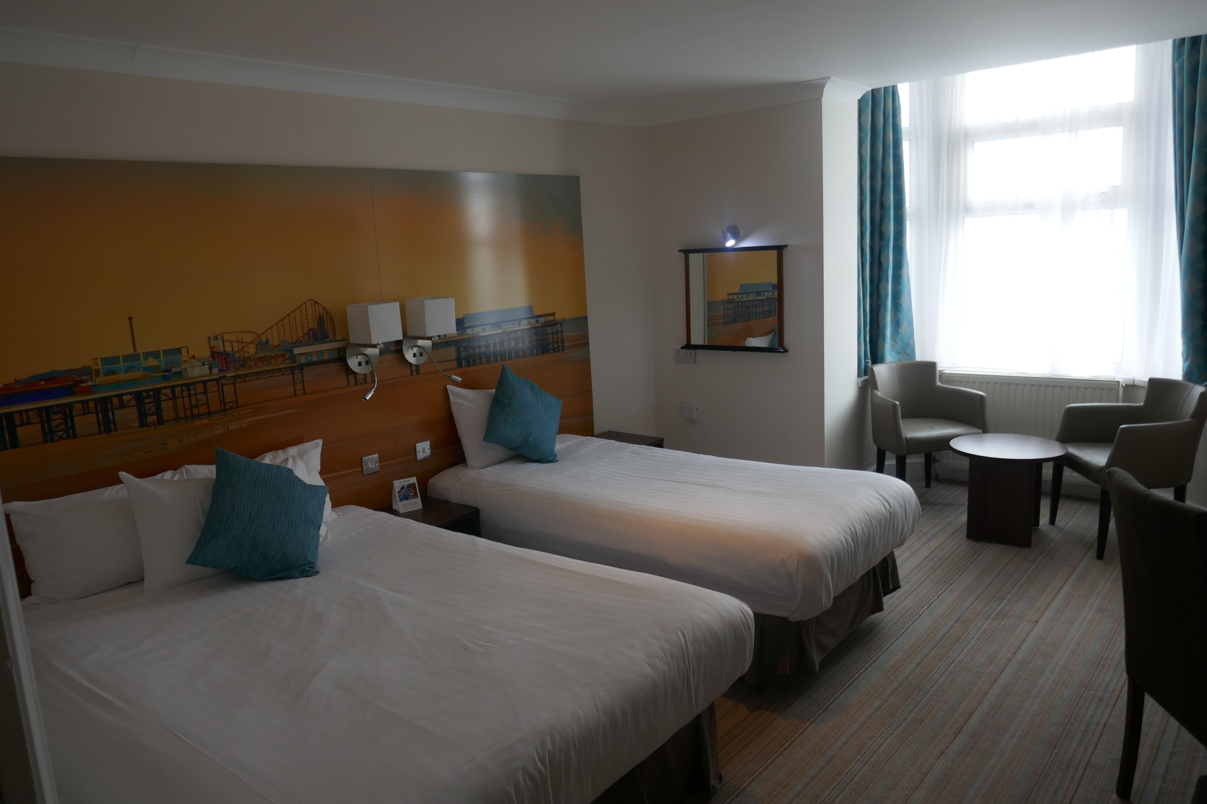 A hotel room with two beds, a small table, and a seating area.