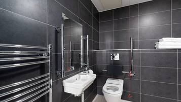 A modern bathroom with a white sink, chrome towel rack, and a toilet.