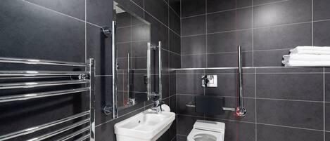 Un baño moderno con lavamanos blanco, toallero cromado y retrete.