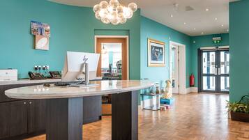 A reception area with a marble counter, a desktop computer, a clock, and a framed picture on the wall.