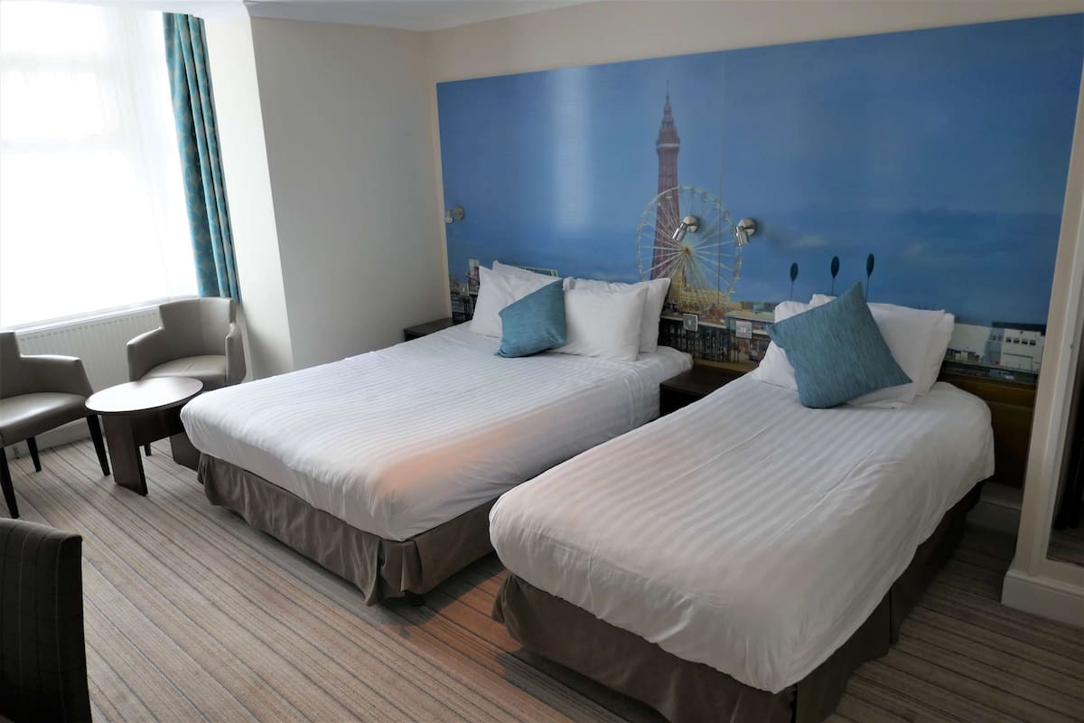 A hotel room with two beds, a small round table, and a chair.