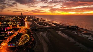 An aerial view of a coastal city at sunset with a prominent tower, a well-lit waterfront promenade, and a beach with visible sand patterns. - Best Western Carlton Hotel (Blackpool)