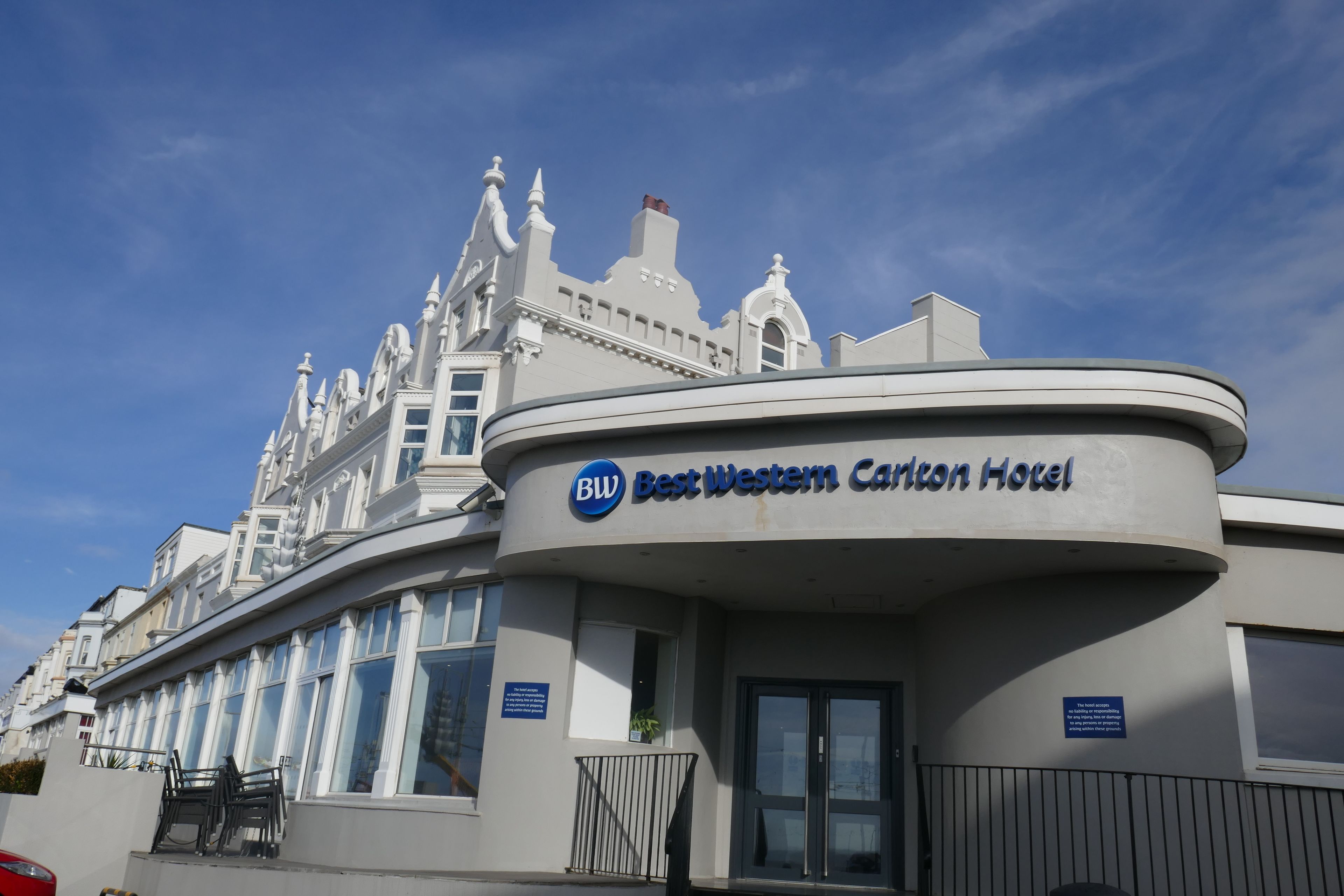 La façade de l’hôtel Best Western Carlton présente un style architectural classique, avec une entrée incurvée remarquable et de grandes fenêtres.