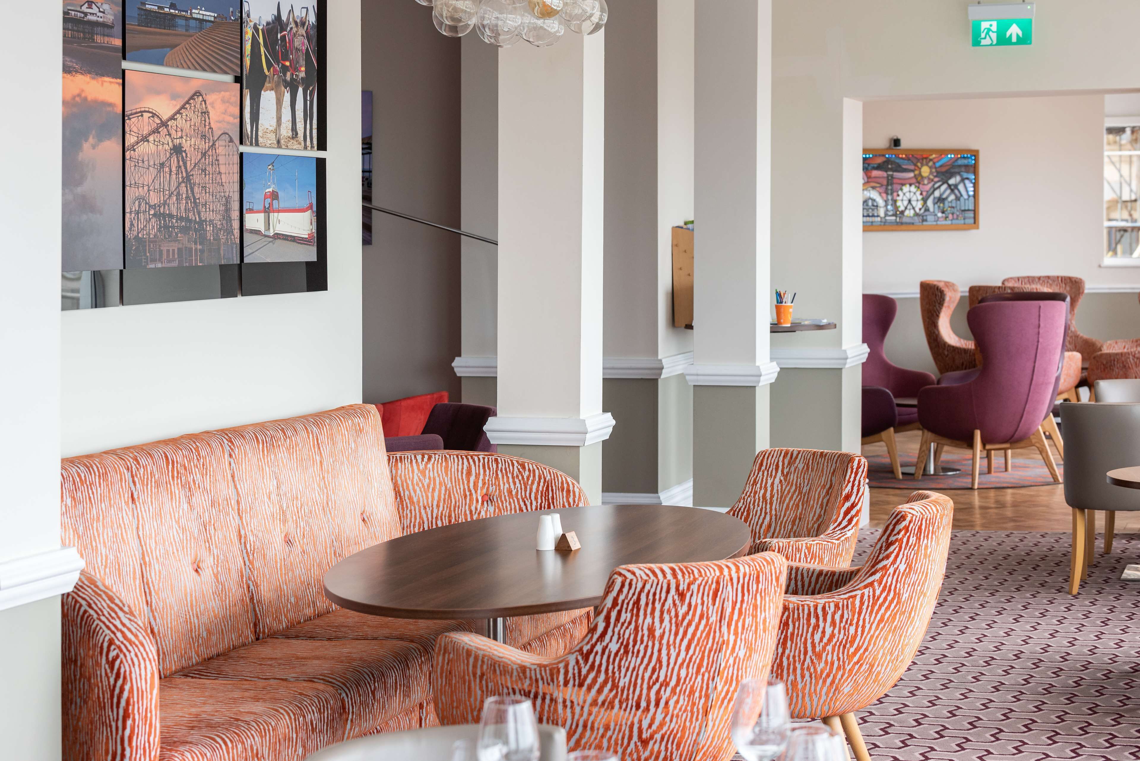 A modern lounge area with patterned seating, a round table, and a wall adorned with framed pictures.
