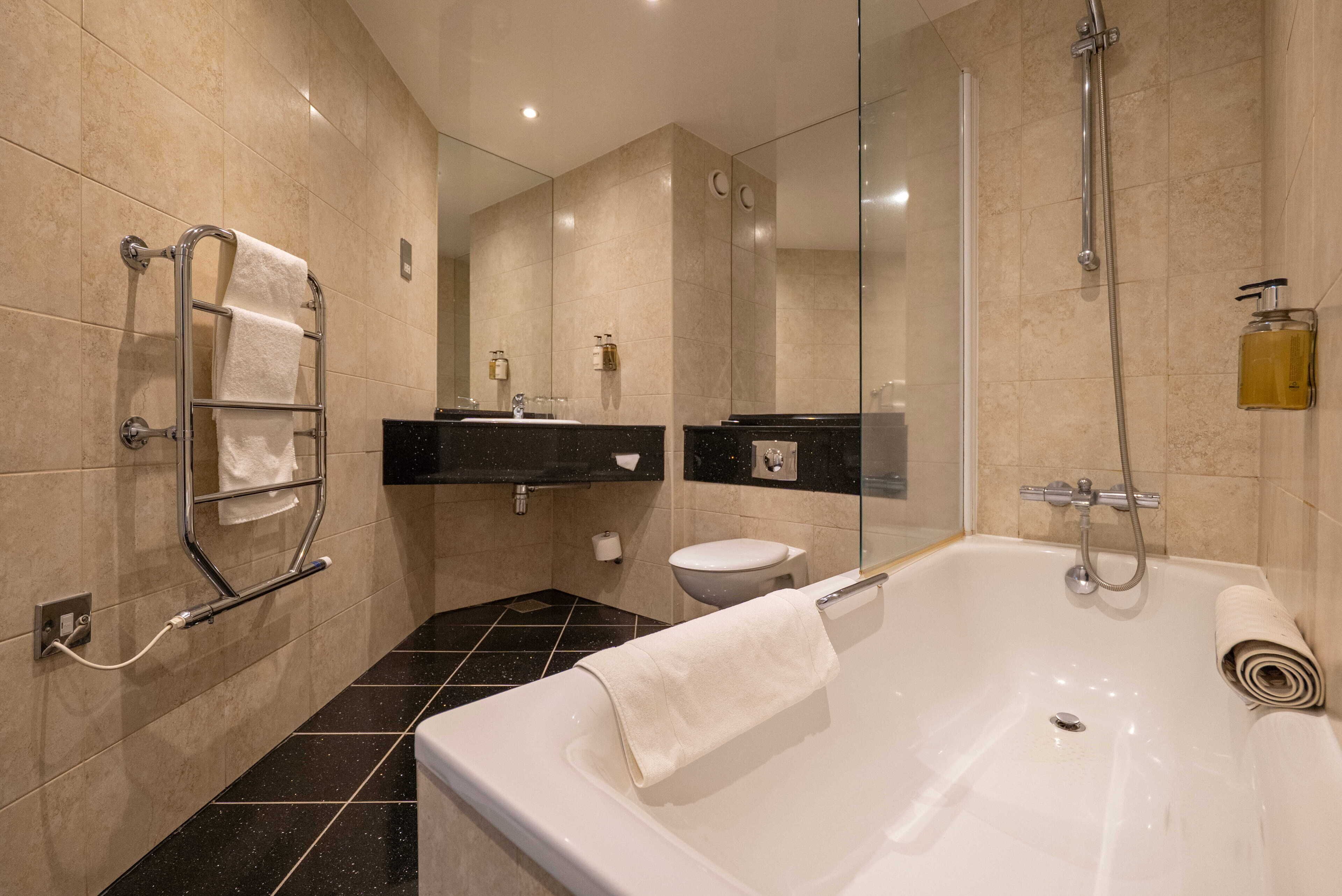 Un baño moderno con bañera, cabina de ducha con vidrio y retrete.