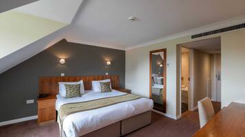 A bedroom with a large bed, bedside lamps, a wooden headboard, and a mirror.